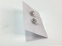 Photo of the earrings from front showing round clear crystals and white rhodium metal setting on a white paper.