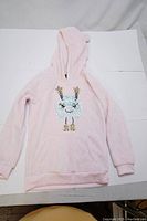 Full view of the light pink hoodie laid flat showing hood, long sleeves, and front sequin design.