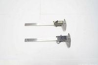 Two Mitutoyo digital calipers laid side by side on flat surface.