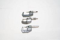 Three Mitutoyo micrometers laid flat, assorted types