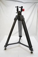 Front view of the Optex tripod standing with legs extended, showing fluid drag pan head and red adjustment knob, without quick release plate or panning control arm