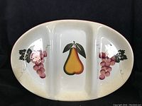 Front view of the large oval divided serving platter showing the hand painted pear in the center and grapes on side compartments.