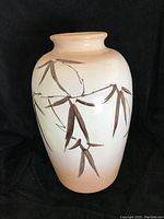Front angle showing full view of large ceramic vase with bamboo leaf design on white and beige background