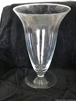 Front view of a large clear glass vase showing its full shape and pedestal base