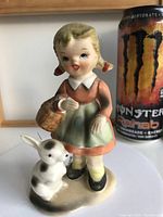 Front view of porcelain figurine depicting little girl with basket and white rabbit