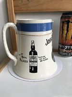 Side view showing printed whiskey bottle label, text, and blue rim
