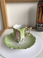 Photo of vintage tea cup with ornate handle and vertical green and pink panels with gold bead accents