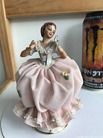 Front view of porcelain figurine showing pink lace dress, face, and fan
