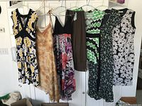 Full view of six lined-up women's dresses in various patterns and colors on hangers