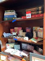 Shelf with assorted books, cat figurines, stuffed cats, and decorative items.