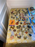 Full view of the costume jewelry laid on a yellow tablecloth including pins and necklaces with holiday themes