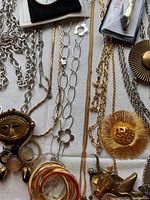 Mixed link chain necklaces, sunburst brooch and gold-tone mask pendant on black cord