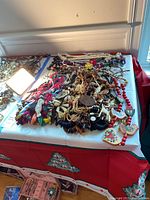Wide view of many necklaces featuring colorful beads, wooden pendants, and floral designs spread on white surface