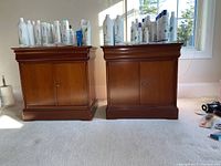Pair of wooden nightstands displayed side by side, showing overall look, finish, and size with bottles on top for scale.