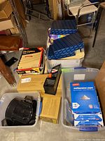 Overview photo showing file folders, multi-purpose paper reams, blue file organizers, and black desk organizers in plastic bins.