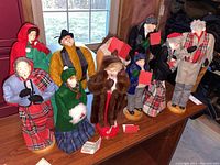 Photo showing 10 handmade Paula Dean dolls arranged on a wooden surface under a window with natural light.