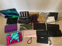 Wide view of all 15 evening bags and clutches arranged on floor showing variety in colors and styles.