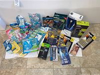All items arranged on floor including razor handle kits, refill cartridges, disposable razors, nose trimmer, electric shavers and mirror pouch