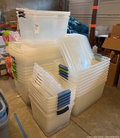 Multiple stacks of clear plastic storage bins of different sizes in a garage setting