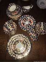 Overhead view of multiple Imari-pattern teacups, saucers, dessert plates, dinner plates and milk jug on wood table