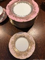 Stack of fourteen pink-bordered 8" plates with one 6" side plate in front