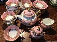 Multiple stacked cups and saucers with teapot, creamer, sugar bowl on table