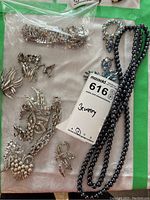 Overview of assorted jewelry pieces including necklace, brooches, earrings, and bracelets laid out on fabric.