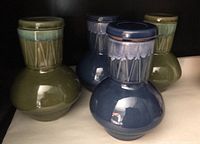 Four Mid-Century Modern style glazed ceramic tea pots in blue and olive green, two of each color, with lids visible on top.