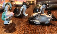 Four Royal Doulton porcelain figurines: three cats and one woman bust, showing hand-painted detail and glossy finish.