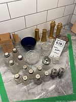 Overview of all items including various salt and pepper shakers, bowls, and measuring glass on a counter with tiled backsplash.