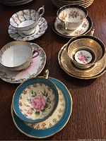 Five teacup and saucer sets displayed on table