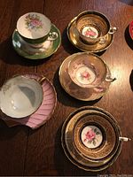 Overview of five teacup and saucer sets arranged on wooden table
