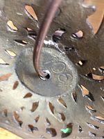 Close-up of metal base cut-out pattern and marking on underside of one lamp base