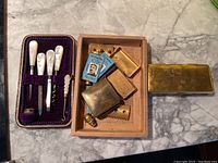 Vintage Gillette razor parts, two packs of blue blades, and small brass razor components arranged on a marble surface