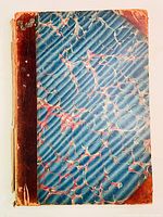 Front cover showing blue marbled paper with red accents and worn leather spine and corners.