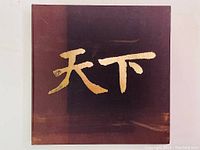 Close up photo of the gilt Chinese characters on the cloth-covered clamshell box housing the book and print.