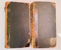 Front covers of two antique scrapbooks showing worn leather binding and edges