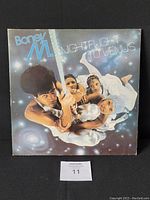 Front cover of Boney M. 1978 Nightflight to Venus vinyl album showing full artwork with band members and cosmic theme, jacket worn at corners