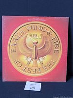 Front cover of Earth Wind & Fire The Best of Vol.1 with gold eagle emblem on orange background.