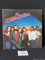 Front cover of The Doobie Brothers 1980 album "One Step Closer" with band members posed in front of a blue and orange sky.