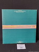 Front cover of album with teal background and abstract horizontal stripe graphic, showing the album title and band name