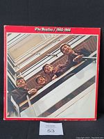 Front cover of The Beatles 1962-1966 double vinyl album with band image leaning over balcony and red border.