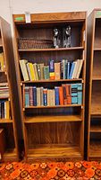 Front view of a wooden four shelf bookcase with various books and a basket on the shelves, showing the overall design and appearance.