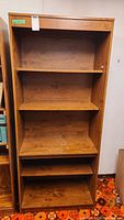 Front view of the wooden four-shelf bookcase showing all shelves and the wood finish.