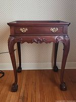 Front view showing the full butlers table with clawed feet, carved legs, drawer and brass handles.