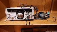 Front view of the Realistic SX-190 shortwave receiver with attached cables and headphones resting on a wood shelf.