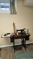 Full view of Singer sewing machine on wooden table with sewing notions placed on top.