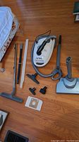 Main photo showing the Eureka HP6855 canister vacuum with its hose, handle, power nozzle, two white wands, floor brush, smaller attachments, and dust bag on wood floor.