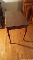 Vintage wooden side table photographed with top and one side visible showing wood grain and cabriole legs