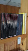 Positioned books on a wood shelf showing the full set of Time-Life Gardeners Guide (15 volumes) in black covers with red titles alongside the Voyage Through the Universe series (4 volumes) in dark covers, a yellow Save the Earth hardback, and a white NGS hardback book.